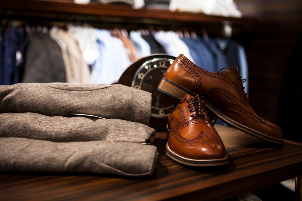 Pair Of Brown Leather Wingtip Shoes Beside Gray Apparel On Wooden Surface 298864