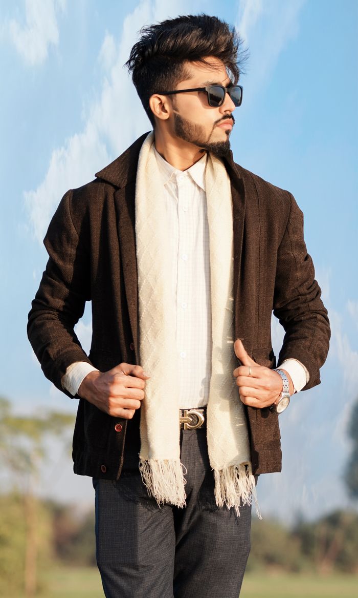 Fashionable adult male in sunglasses and scarf posing confidently outdoors.